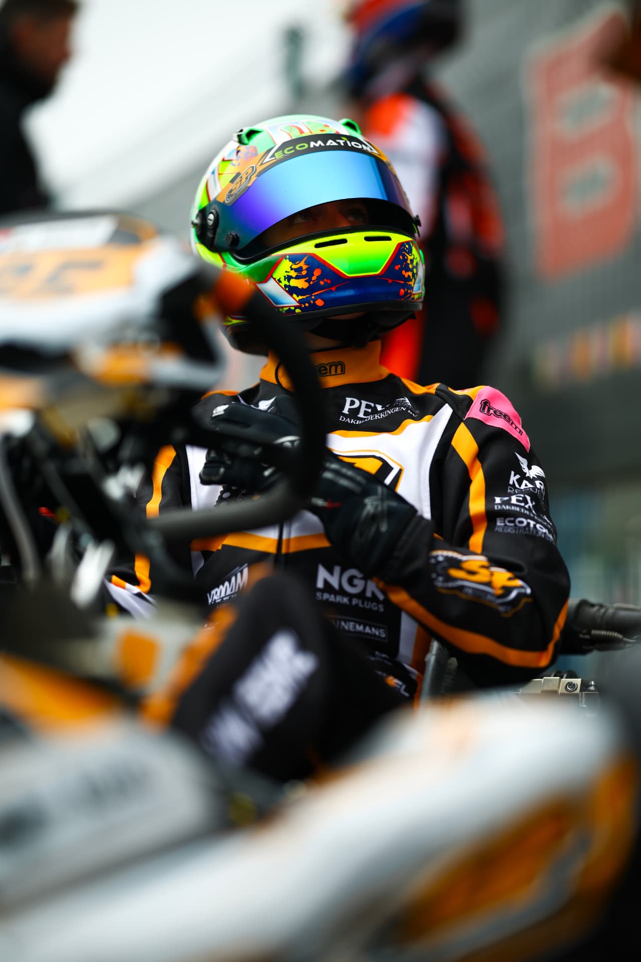Lieke van Boekel in her kart, helmet on, seen through the steering wheel